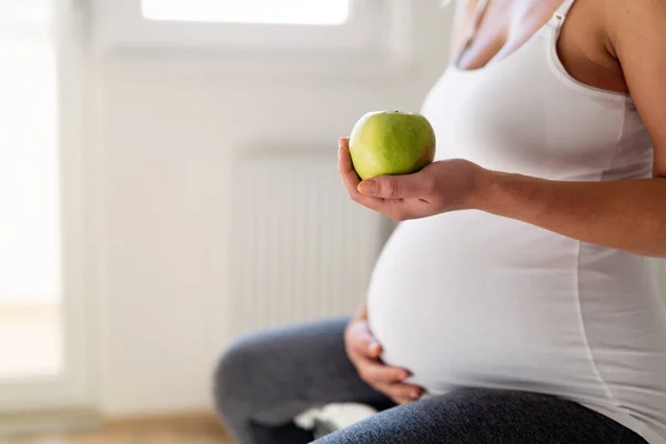 Беременная женщина ест яблоко — стоковое фото