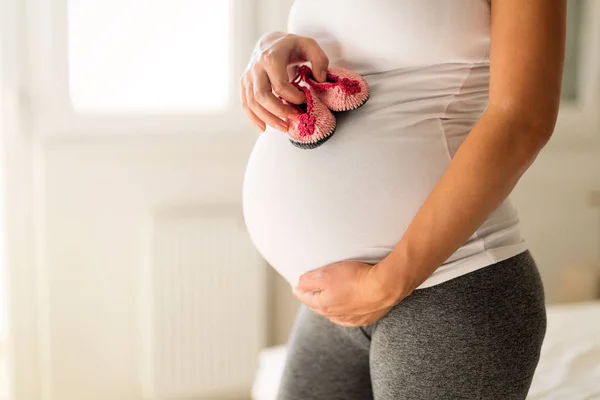 Pregnant woman holding newborn shoes — Stock Photo, Image