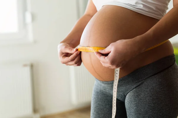 Mujer embarazada midiendo el diámetro del vientre — Foto de Stock