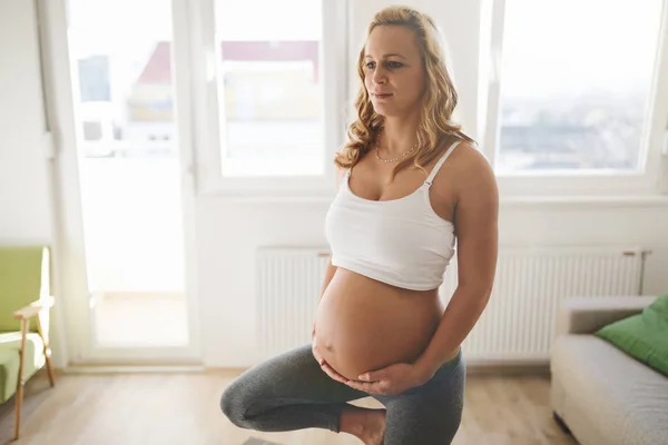 Осуществление беременной женщины дома — стоковое фото