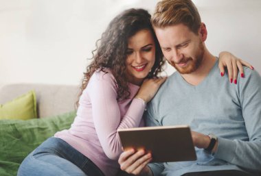 Mutlu çift evde tablet üzerinde sörf