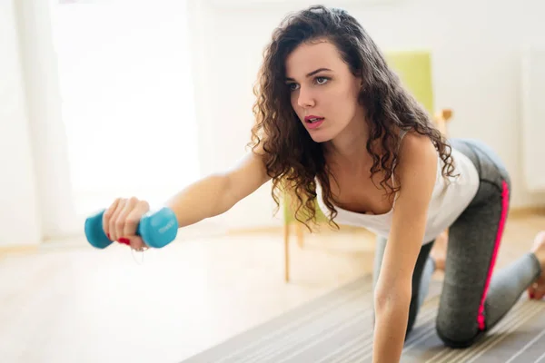 Sportliche Frau trainiert zu Hause, um fit zu bleiben — Stockfoto