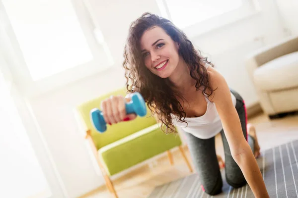 Sportliche Frau trainiert zu Hause, um fit zu bleiben — Stockfoto