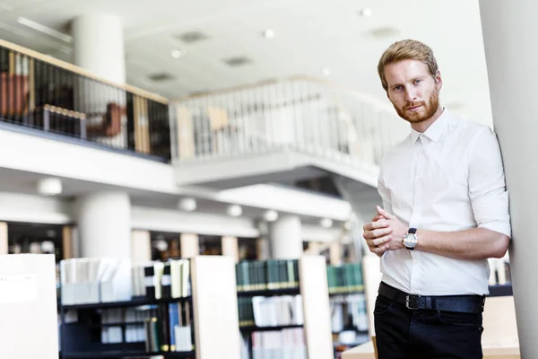 Étudiant beau sérieux dans la bibliothèque — Photo