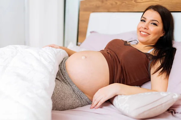 Молодая беременная женщина в постели — стоковое фото
