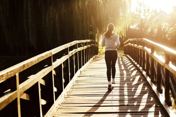 Linda jogger feminino correndo durante o pôr do sol — Fotografia de Stock