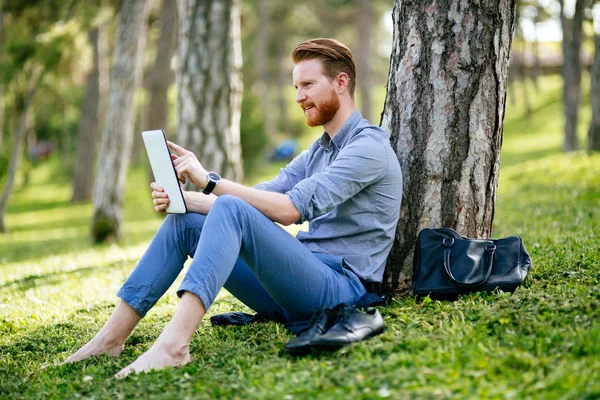 Parkta tablet kullanan bir işadamı