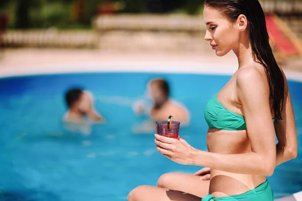 Žena se těší koktejl u bazénu — Stock fotografie