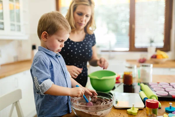 Έξυπνη χαριτωμένο παιδί, βοηθώντας την μητέρα του στην κουζίνα — Φωτογραφία Αρχείου