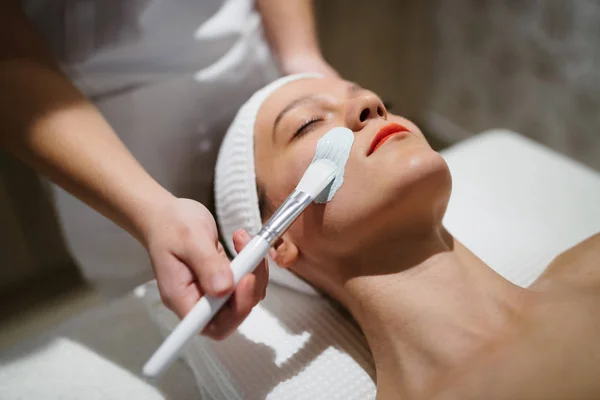 Masseur aplicando máscara facial — Fotografia de Stock