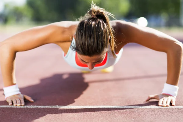 Woman doing push-ups outdoors Stock Photo