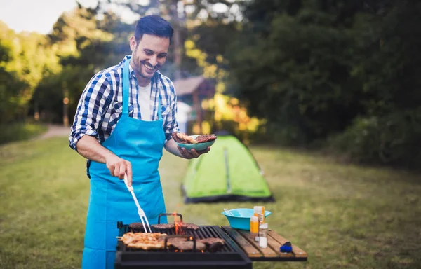 Lykkelig mann som tilbereder bbq-kjøtt – stockfoto