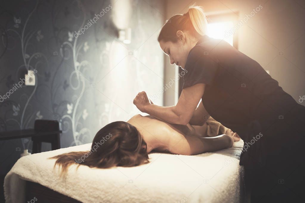 Masseur massaging female client at resort