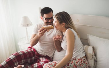 Çift yatakta kahvaltı yapıyor.