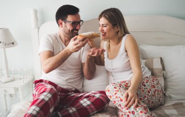 Çift yatakta kahvaltı yapıyor.