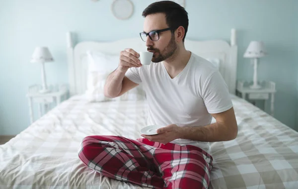 Mand i pyjamas nyder kaffe - Stock-foto