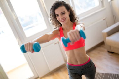 Kadın dambıllarla çalışıyor.