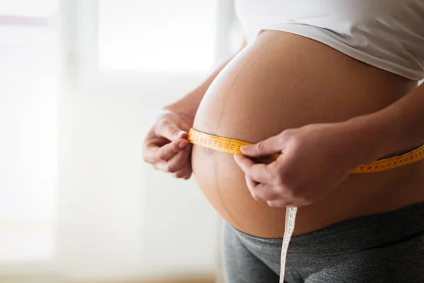 Mujer embarazada midiendo su vientre — Foto de Stock