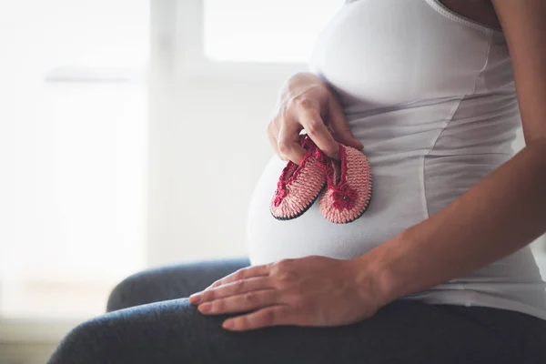 Moeder houden babyslofjes op buik — Stockfoto