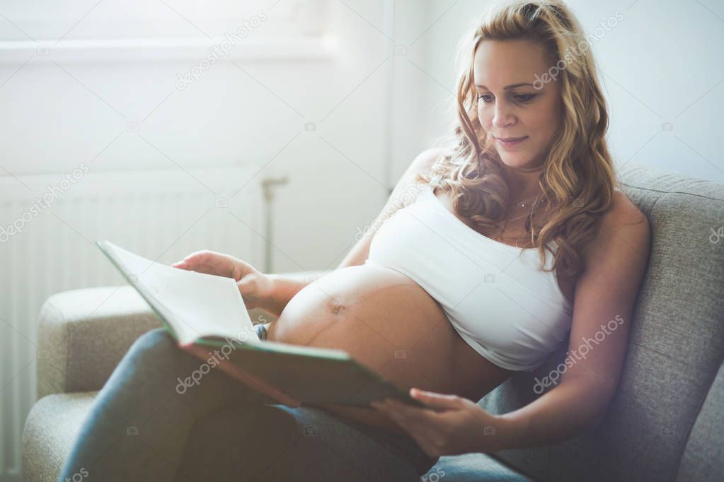 Beautiful pregnant woman reading book