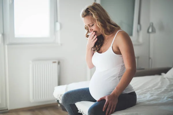 Красивая беременная женщина лежит в постели с судорогами — стоковое фото
