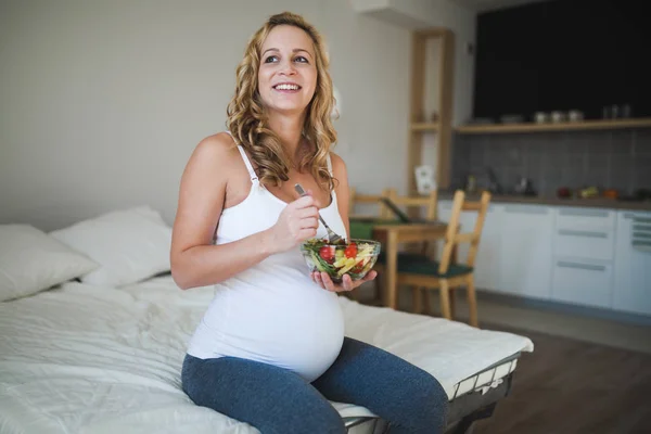 Беременная женщина ест салат — стоковое фото