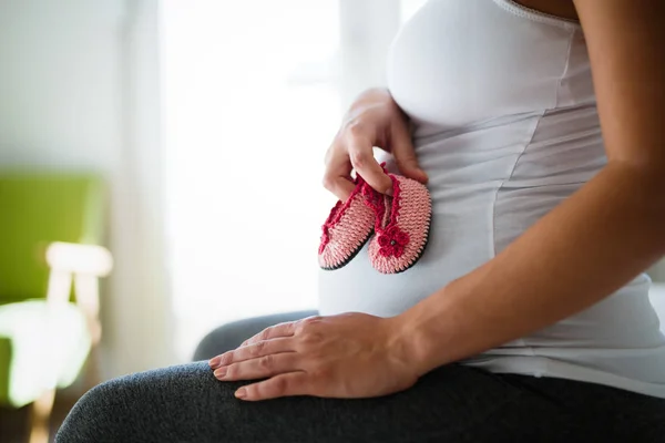 Moeder houden babyslofjes op buik — Stockfoto