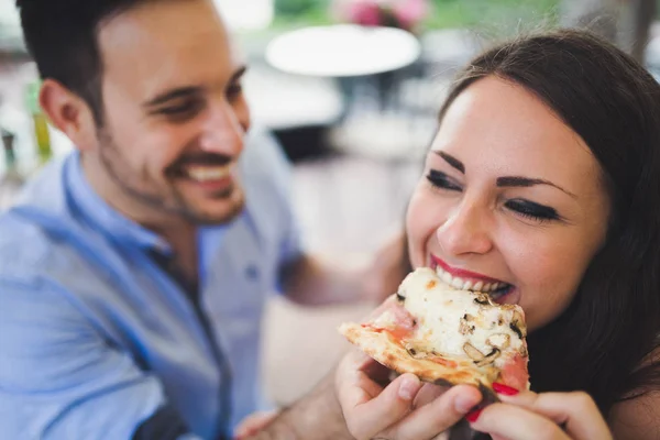 Пара делится ломтиком пиццы в кафе — стоковое фото