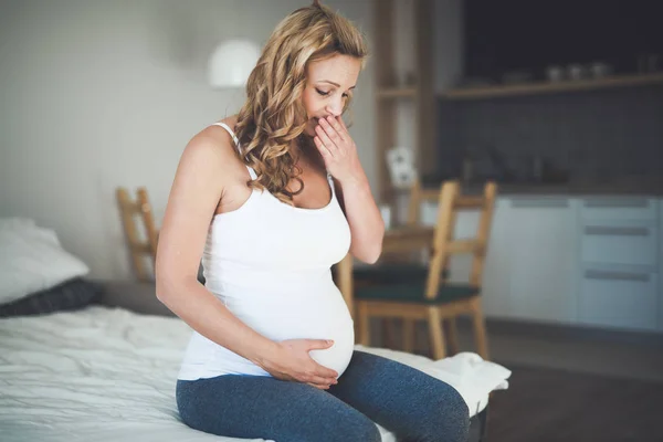 Красивая беременная женщина лежит в постели с судорогами — стоковое фото