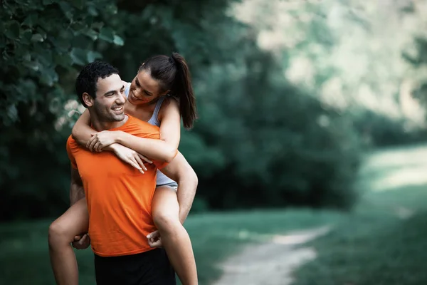 Vriendin rijden op man in park — Stockfoto