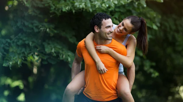 Girlfriend riding on man in park — Stock Photo, Image