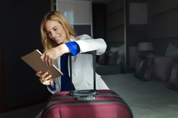 Mulher com mala usando tablet — Fotografia de Stock