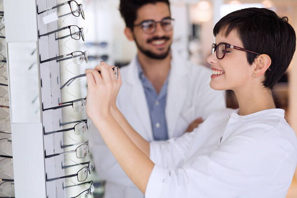 woman with optician trying eyeglasses