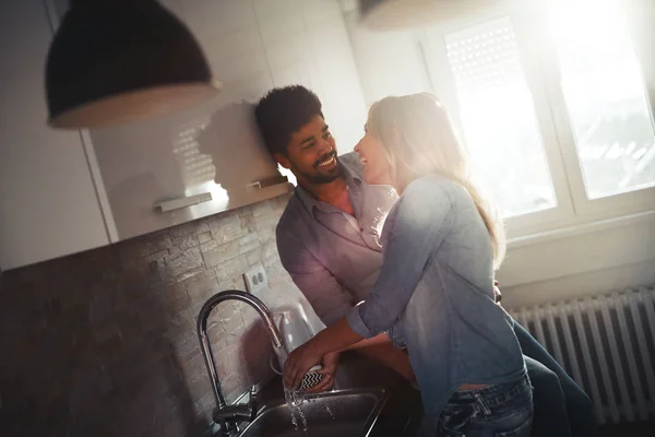 Молодая пара моет посуду на кухне и улыбается — стоковое фото