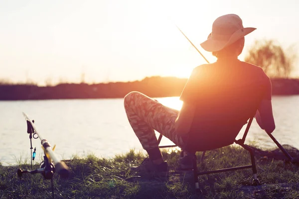 Jovem pesca no lago ao pôr do sol desfrutando de hobby — Fotografia de Stock