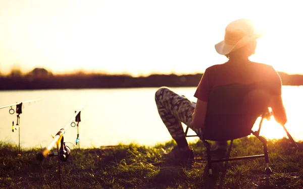 Giovane pesca sul lago al tramonto godendo hobby — Foto Stock