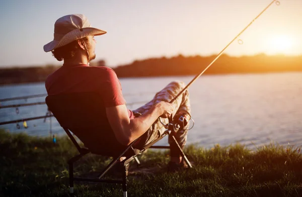 Мужчины рыбачат на закате и расслабляются, наслаждаясь хобби — стоковое фото