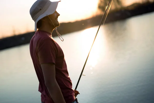 Young man fishing at pond and enjoying hobby — Stock Photo, Image