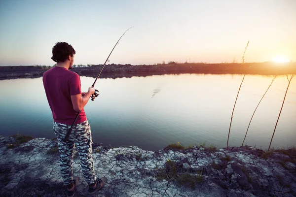 Giovane uomo pesca allo stagno e godendo hobby — Foto Stock