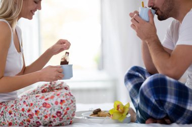 Çift yatakta kahvaltı yapıyor.