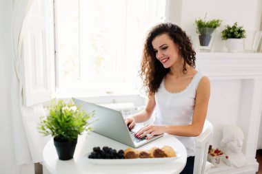 kadın gülümsüyor ve dizüstü bilgisayar kullanarak