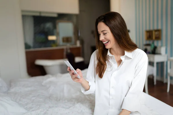 Vrouw met behulp van de telefoon op bed — Stockfoto