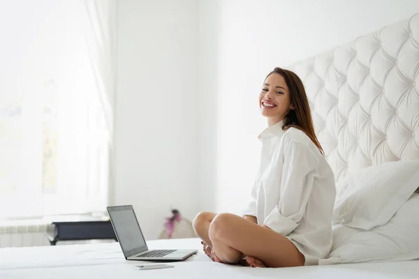 Mooie vrouw zittend op haar bed — Stockfoto