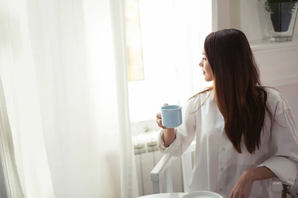 Mujer con taza de café sentado en la mesa —  Fotos de Stock