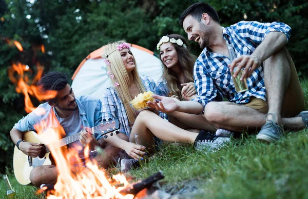 Fröhliche junge Freunde amüsieren sich am Lagerfeuer — Stockfoto