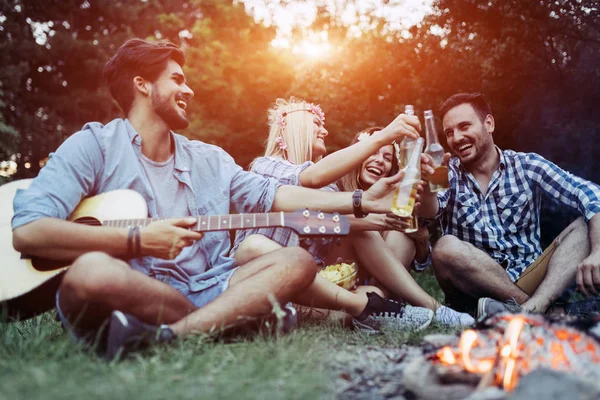 Fröhliche junge Freunde amüsieren sich am Lagerfeuer — Stockfoto