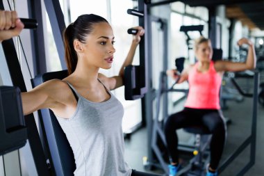Genç kadın spor salonunda makinede egzersiz