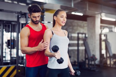 Spor salonunda antrenör ile çalışma dışarı genç yetişkin kadın