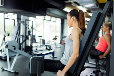 Genç kadın spor salonunda makinede egzersiz