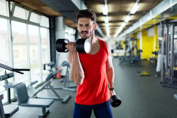 Gespierde bodybuilder training in de sportschool doen biceps oefeningen — Stockfoto